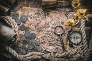 Image of pirate treasure, a compass, a spyglass and a skull on a table
