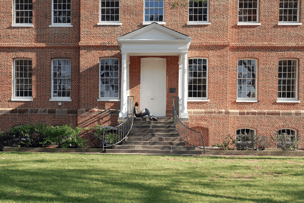 Image of a student studying on the steps of a dorm at St. John's College in Annapolis, one of the oldest U.S. colleges, featured in an article about America's 50 oldest colleges and universities.