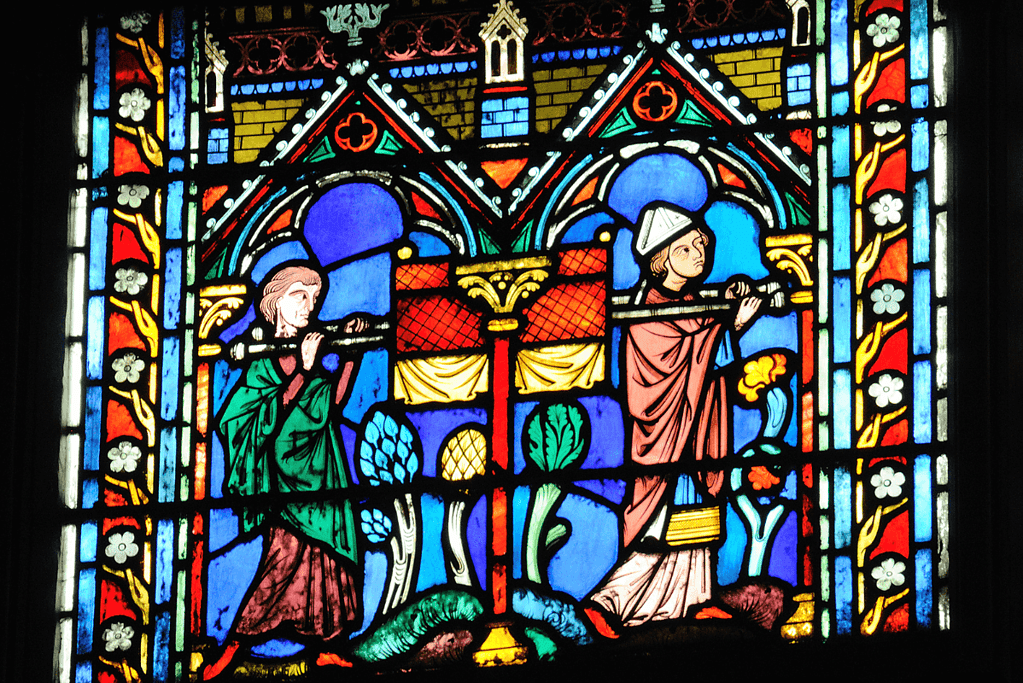 Image of a stained glass window showing two individuals carrying the Ark of the Covenant