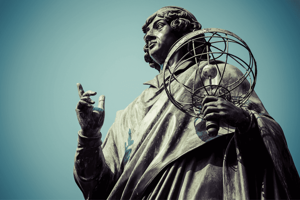 Statue of Copernicus, one of the famous astronomers, clasping an astrolabe, symbolizing his contributions to astronomy.