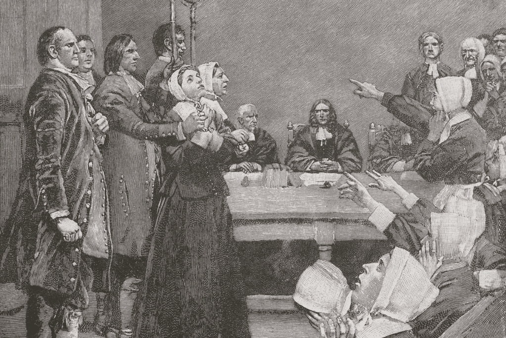 Image of an artistic representation of a 17th-century courtroom during the Salem Witch Trials, with accused witches at the center, surrounded by a sea of accusatory faces and stern judges.