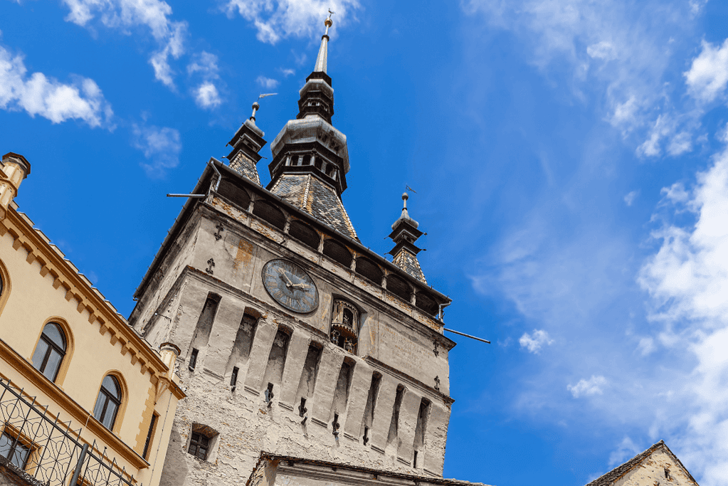 Image of the historic clocktower in Sighişoara, Romania its gothic architecture silhouetted against the sky, marking the origins of the legendary figure, Vlad the Impaler.