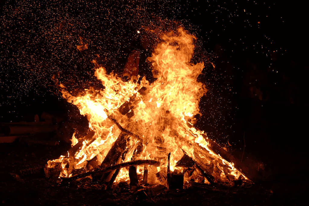 Image of a vibrant bonfire set against a night sky, symbolizing the medieval tradition of souling celebrations, which played a pivotal role in shaping what we know today as Halloween, part of the broader Halloween history timeline.