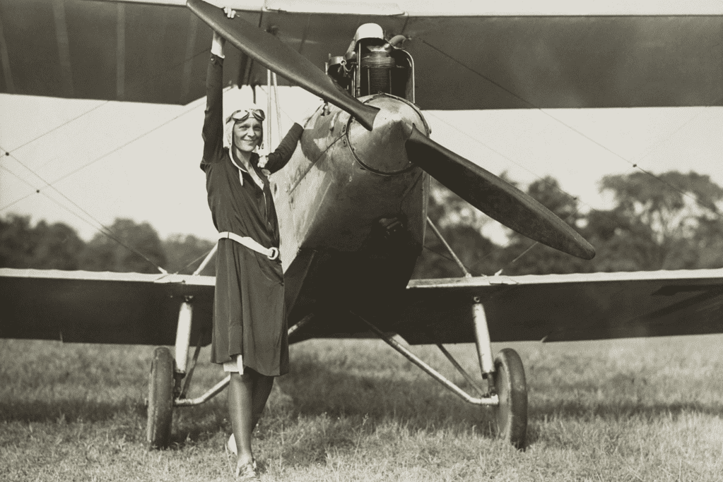 Image of aviation pioneer Amelia Earhart at the front of a bi-plane for an article covering interesting facts about Amelia Earhart