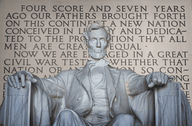 Image of the statue of Abraham Lincoln at the Lincoln Memorial in Washington, D.C. with the Gettysburg Address imprinted in the wall behind Lincoln, for an article covering 10 interesting facts about the Gettysburg Address.