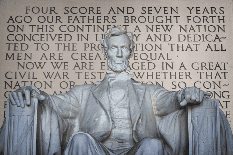Image of the statue of Abraham Lincoln at the Lincoln Memorial in Washington, D.C. with the Gettysburg Address imprinted in the wall behind Lincoln, for an article covering 10 interesting facts about the Gettysburg Address.