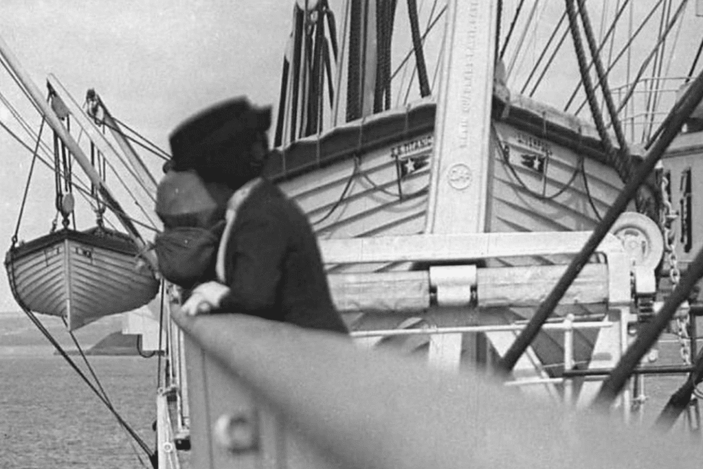 Image of a Titanic passenger looking towards the lifeboats, unaware of the limited number of lifeboats on the ship prior to the tragic event.