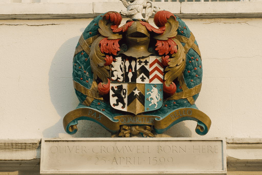 Image of the Cromwell family crest and a marker on the birthplace of Oliver Cromwell.