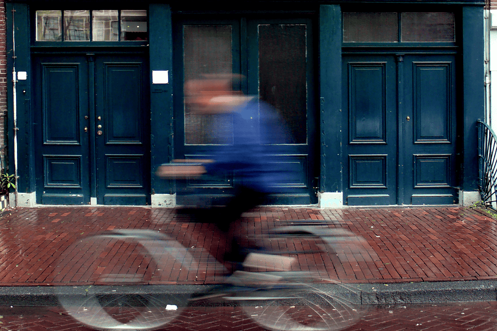 Image of a blurred out bicycle rider riding past the Frank home in Amsterdam.