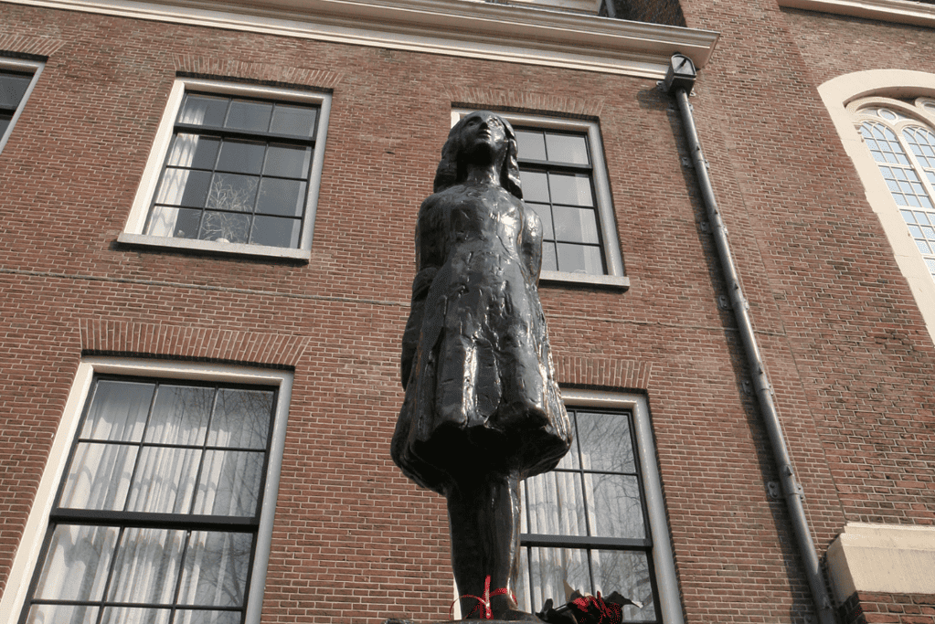 Image of a memorial statue of Anne Frank standing in defiance.