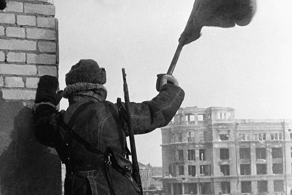 Image of a soldier waving the flag of the Soviet Union following their victory at Stalingrad for a blog post covering the Battle of Stalingrad timeline.