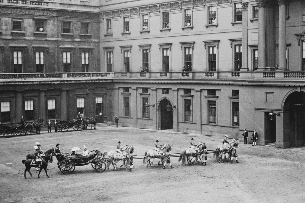 Image of Queen Victoria returning to Buckingham Palace via horse and carriage.